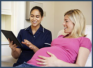 Nurse Using Digital Tablet In Meeting With Pregnant Woman
